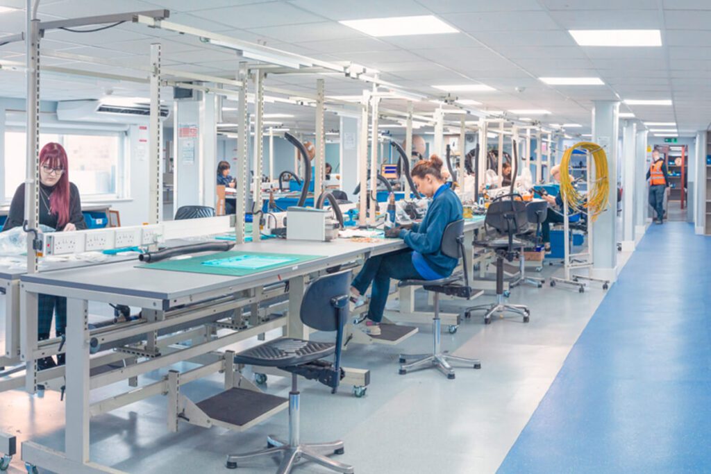 A team of people working at desks in a brightly lit workshop