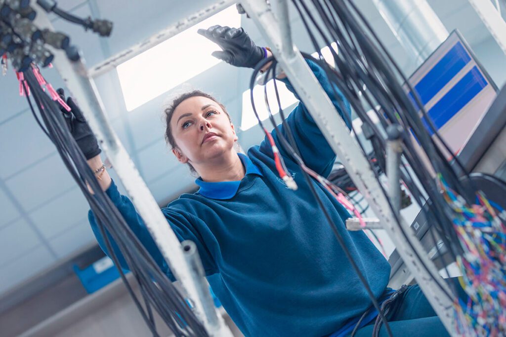 Women wearing gloves inspecting cable harness